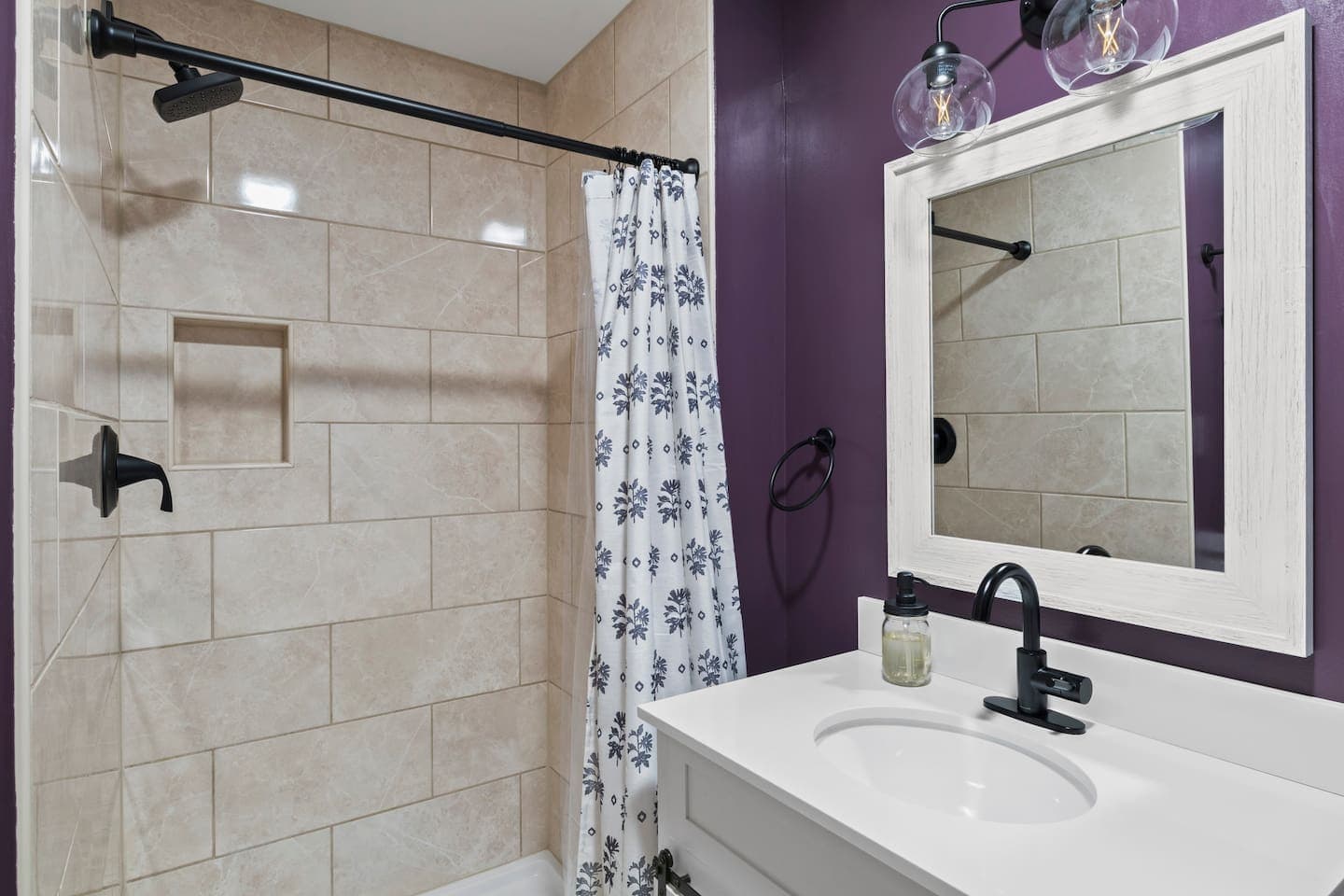 Bathroom with tiled shower and dark fixtures