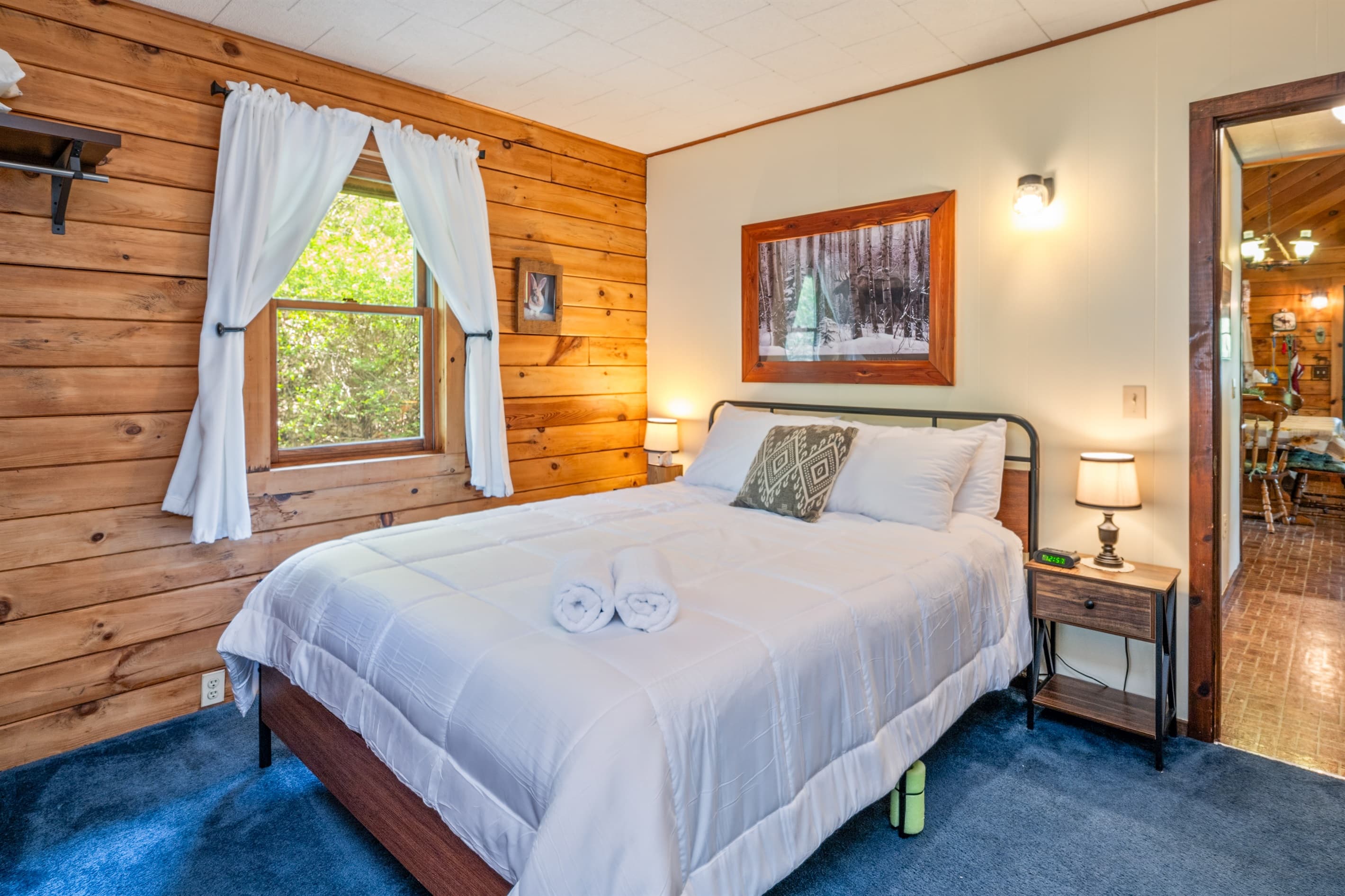 Bed beside window with white curtains