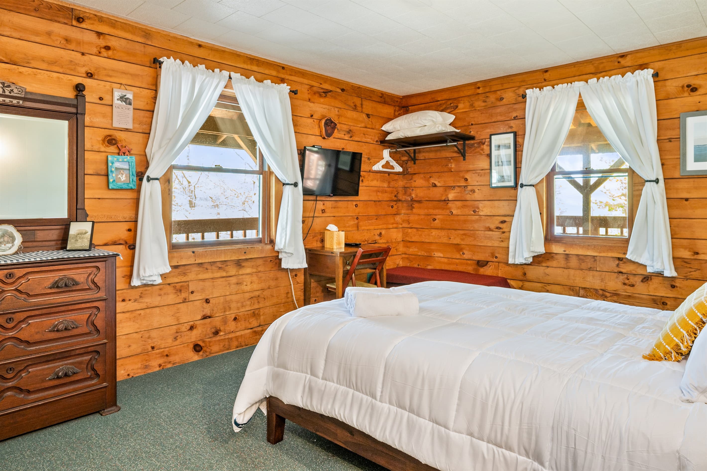Bedroom with dresser and curtained windows