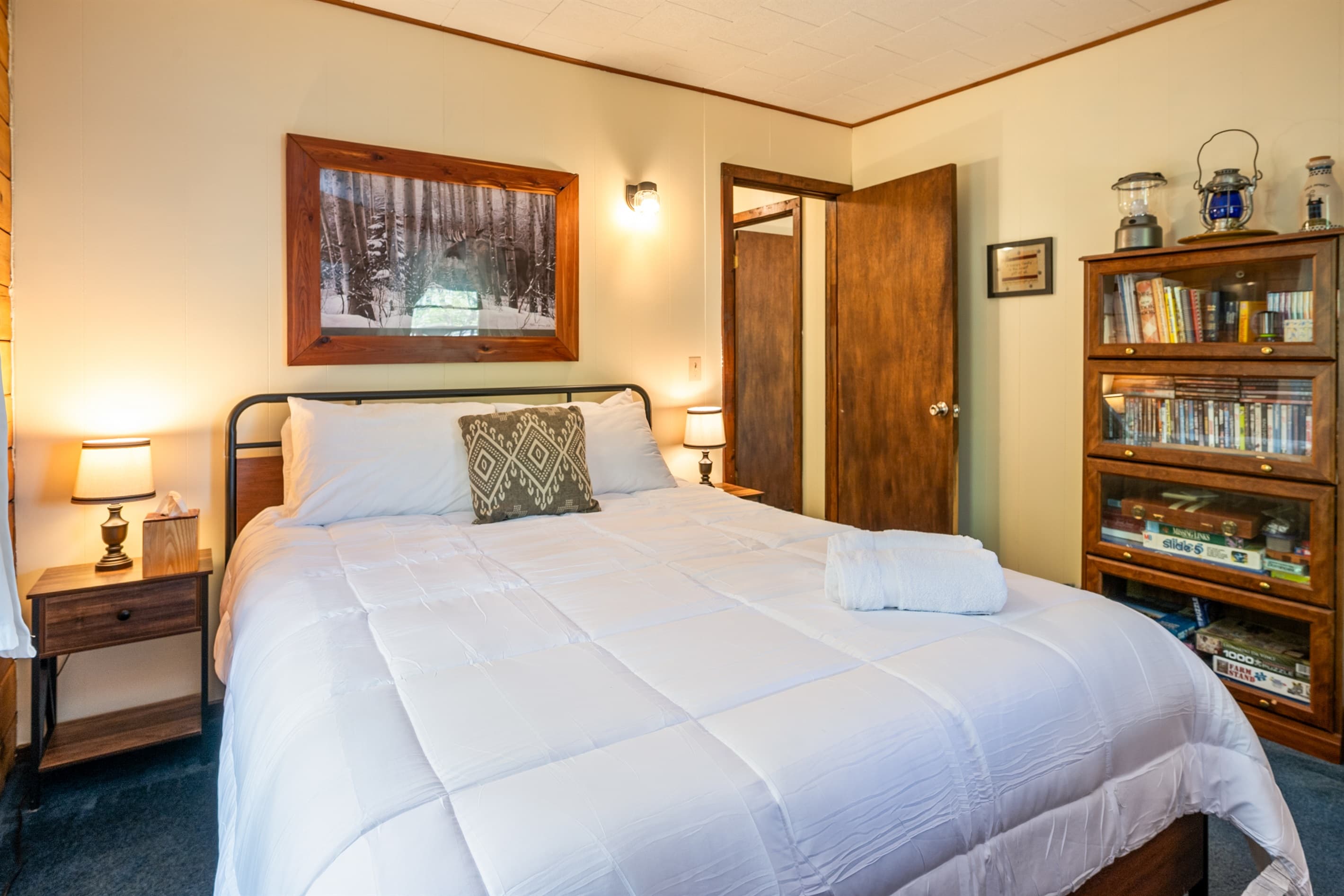 Bed beside wooden nighstand and bookshelf