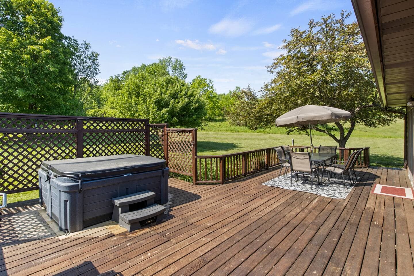 Deck with hot tub, dining table, and umbrella