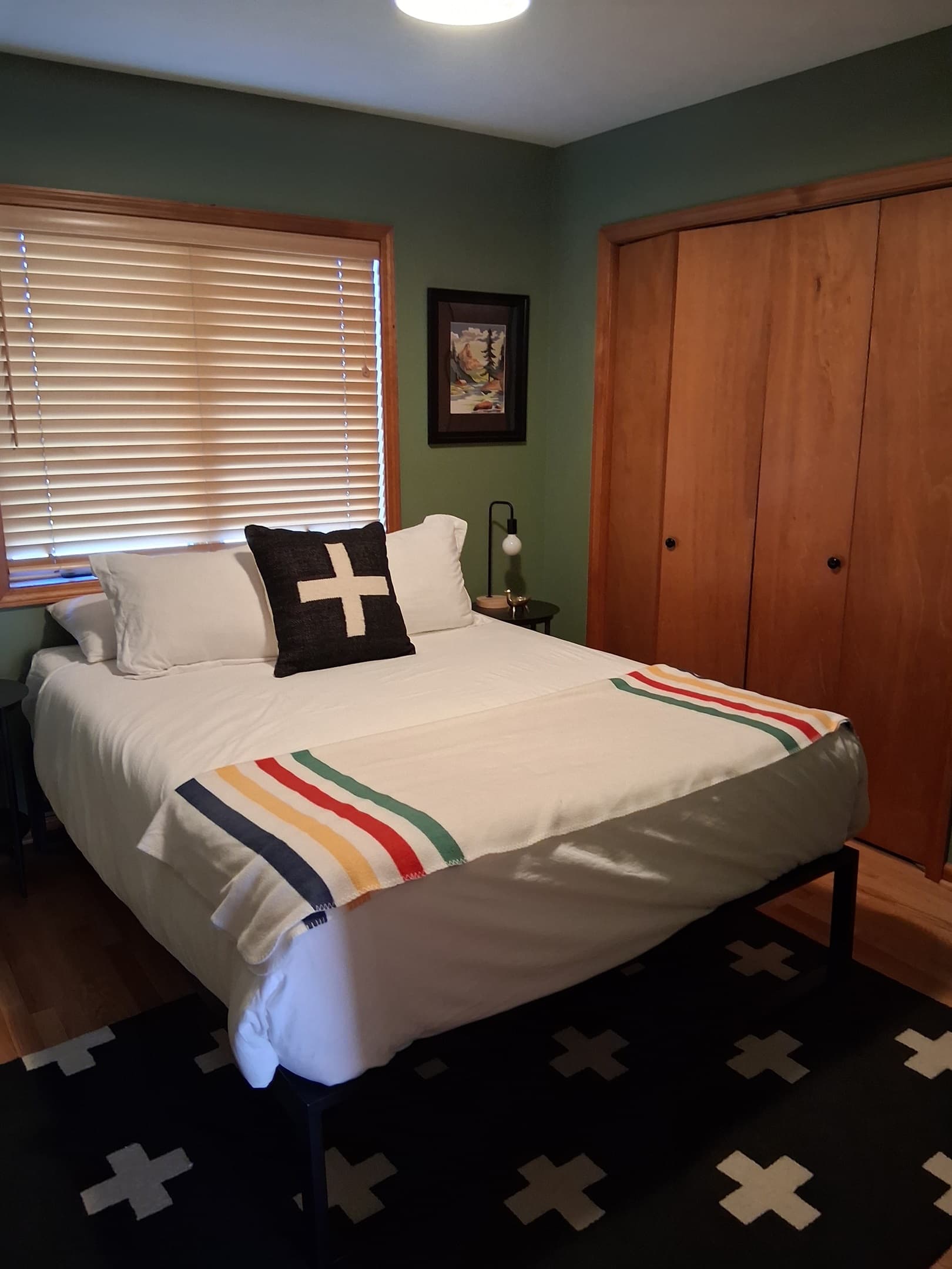 Bedroom with striped throw and wooden closet doors