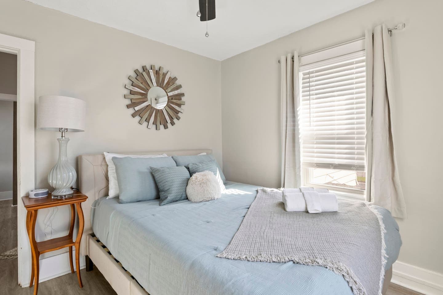Bedroom with blue linens and sunburst mirror