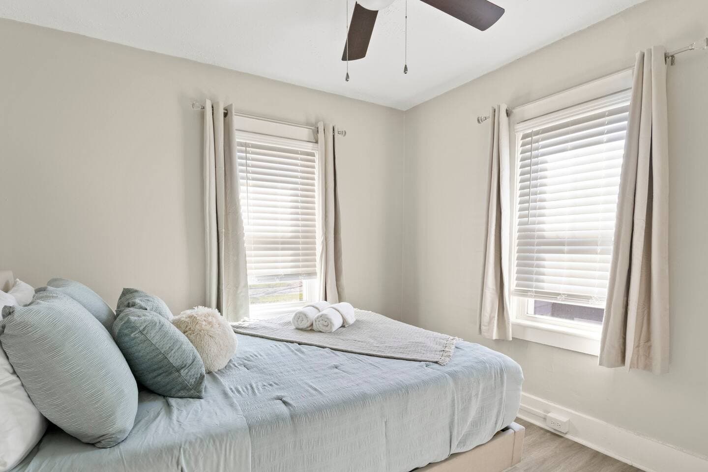 Bedroom with large windows and neutral bedding