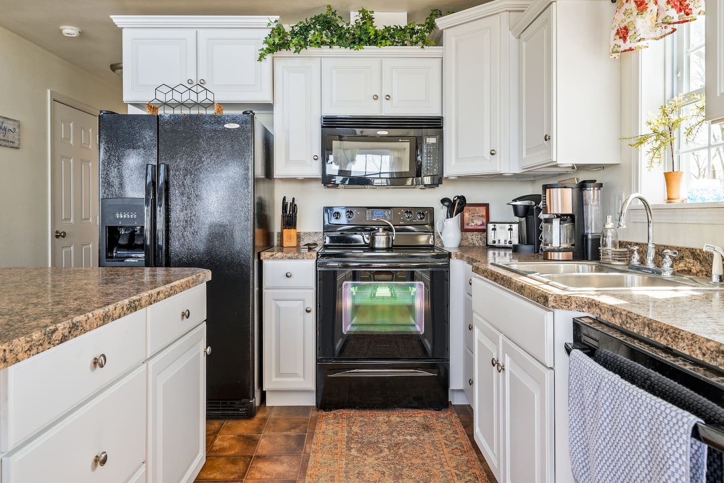 Kitchen with black appliances and white cabinetry