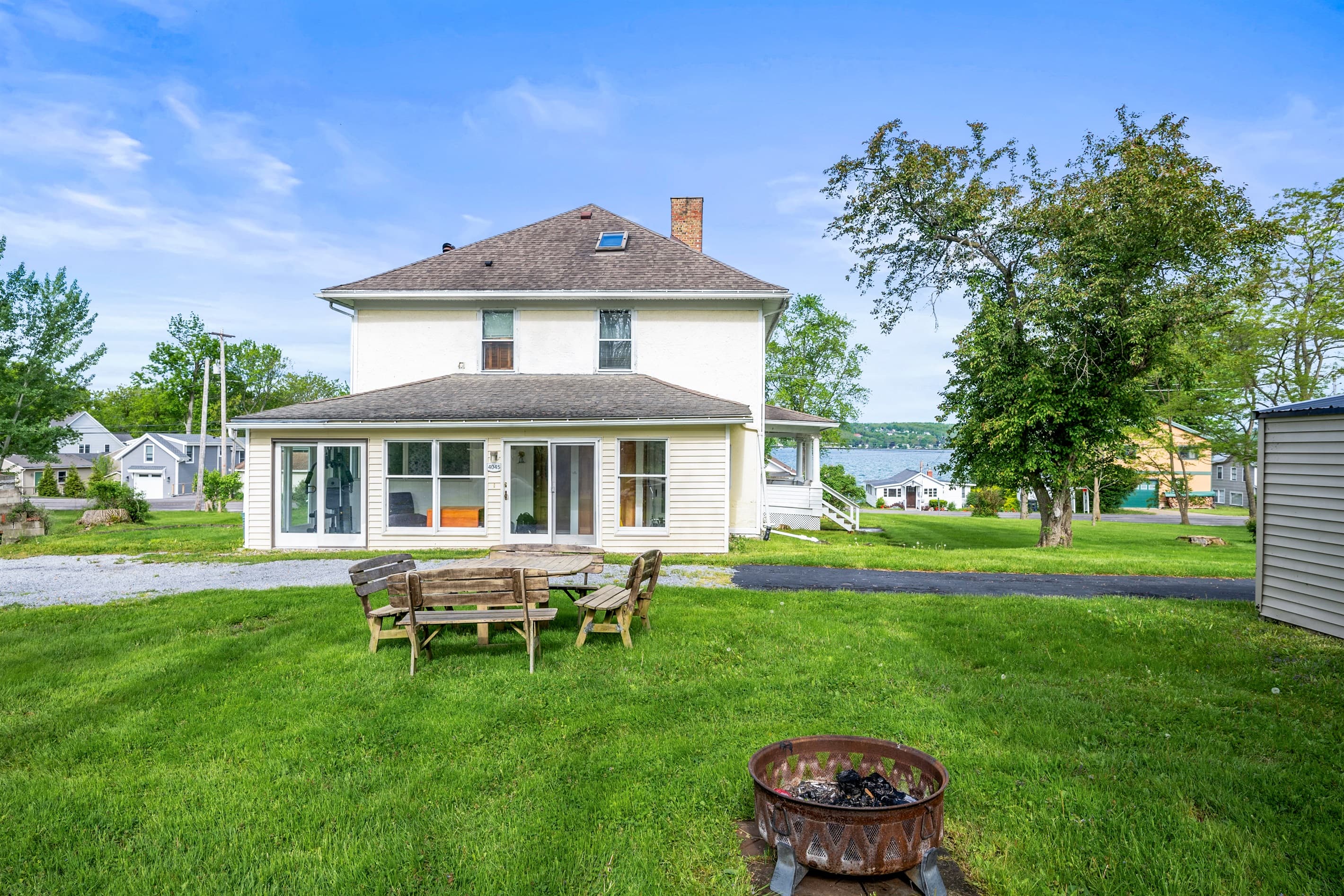 White farmhouse overlooking grassy fire pit area