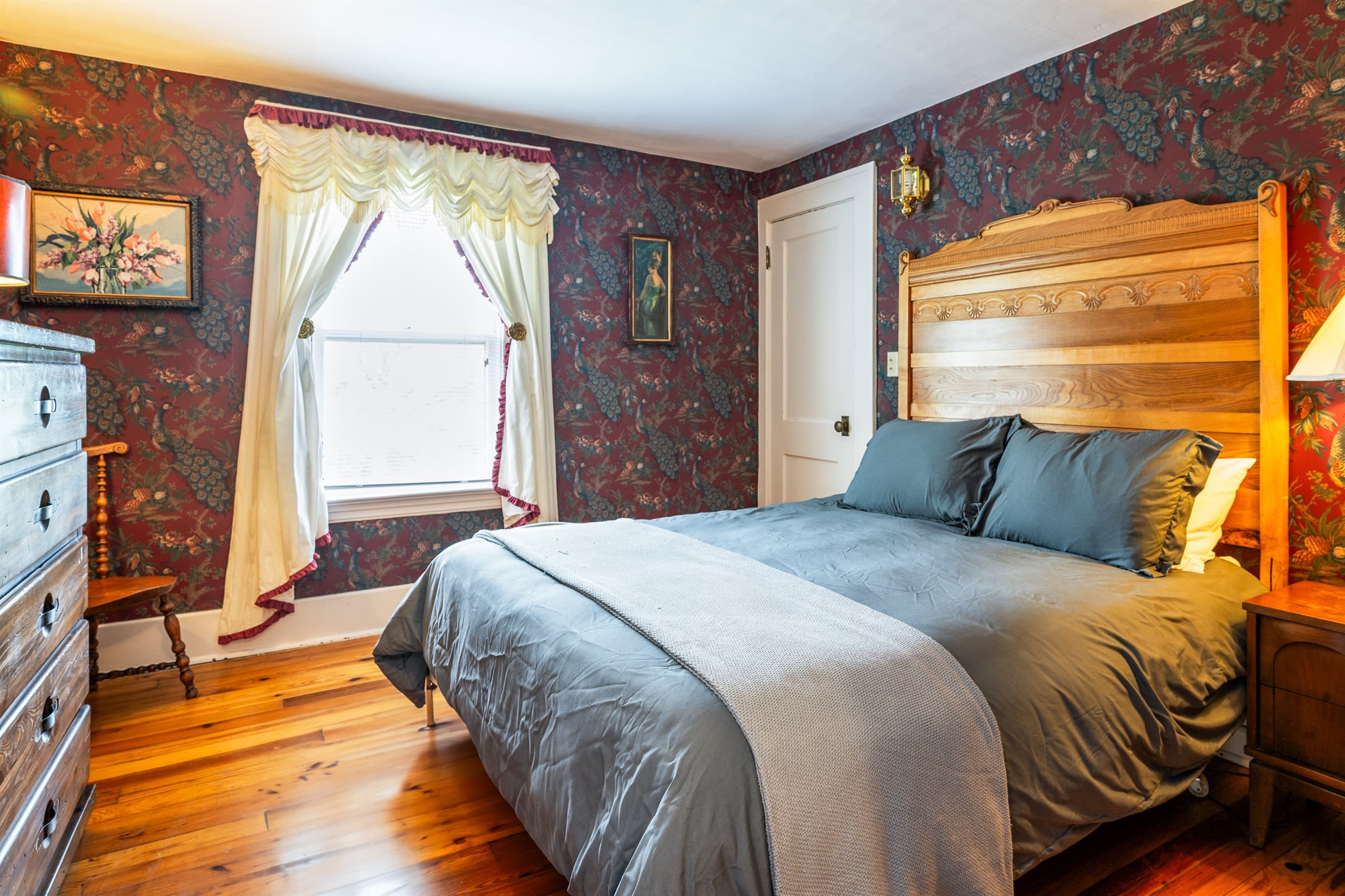 Bedroom with wooden dresser and curtained window