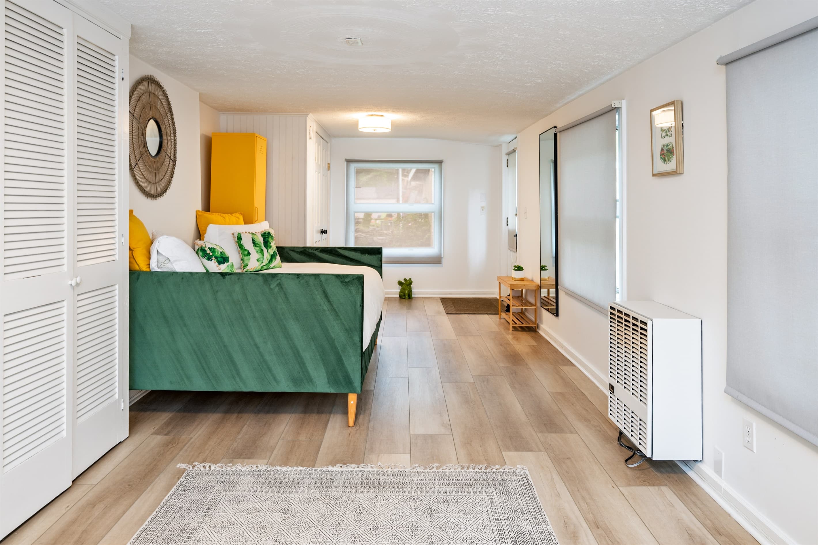 Entryway with green studio bed across the window 