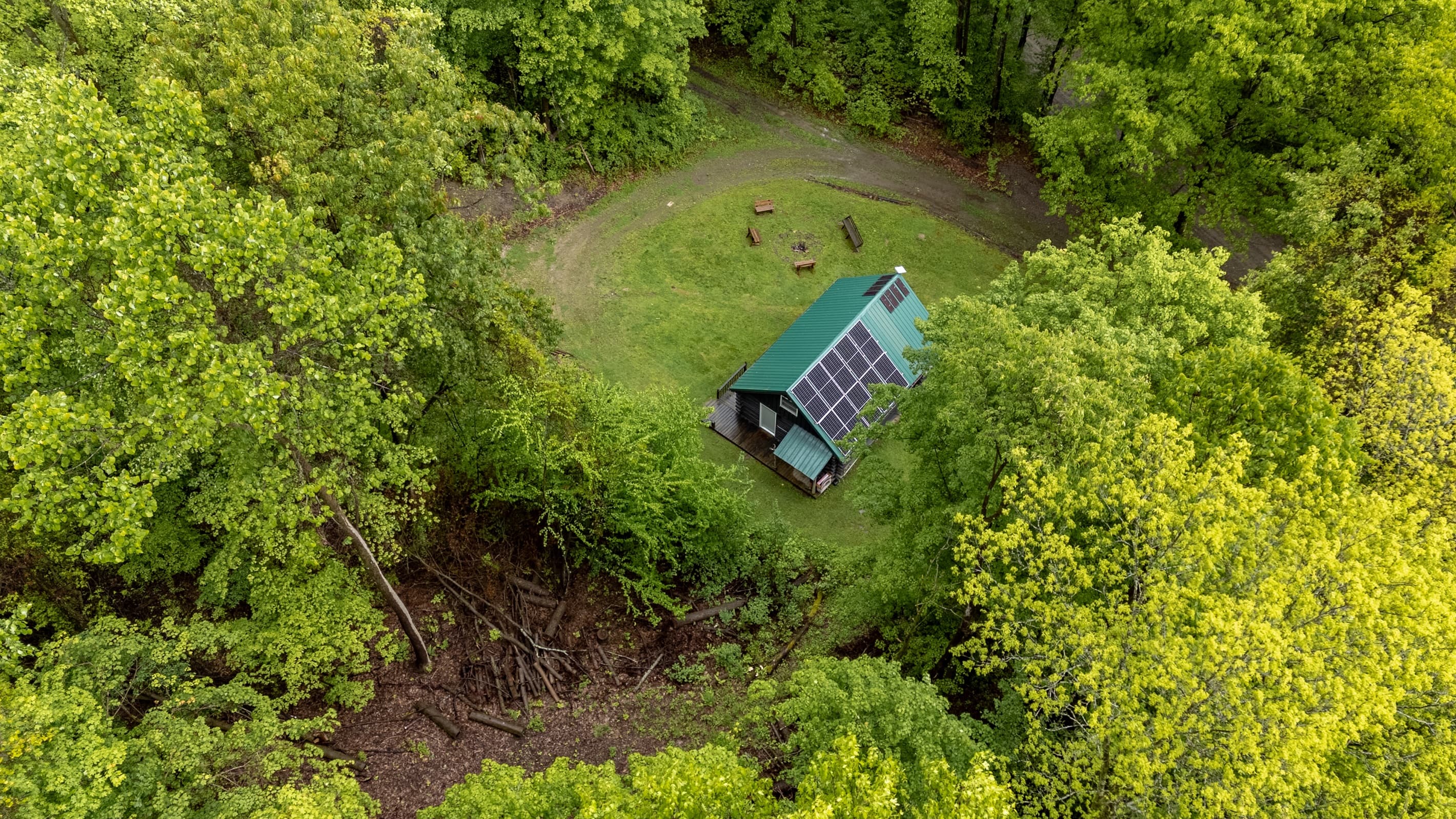 Aerial view of cabin and wooded clearing