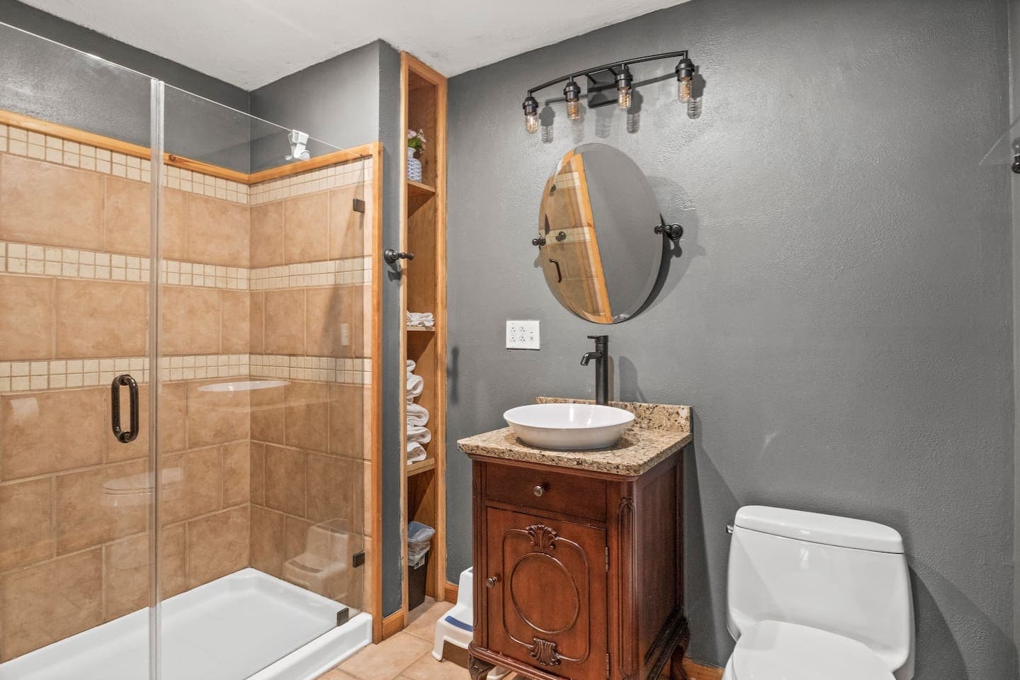 Bathroom with vessel sink and wooden cabinets and shelving 