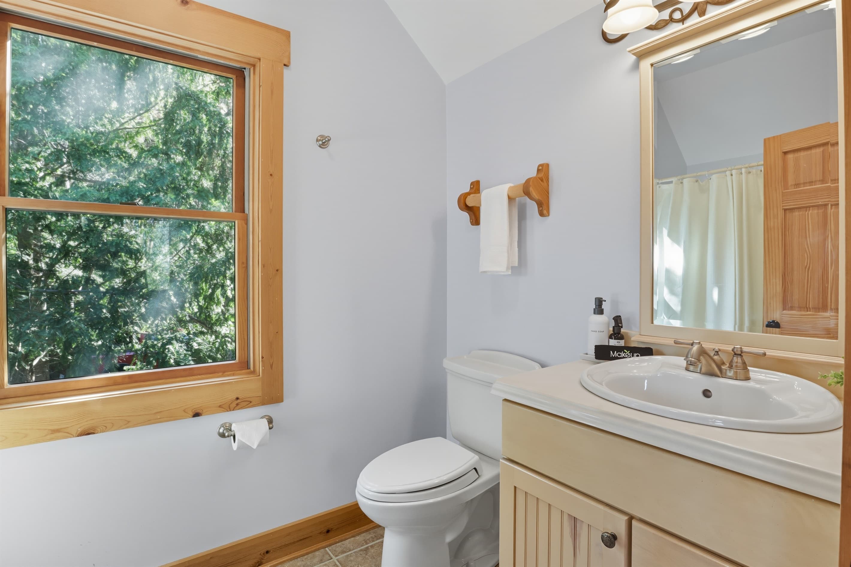 Bathtub beneath a wooded-view window