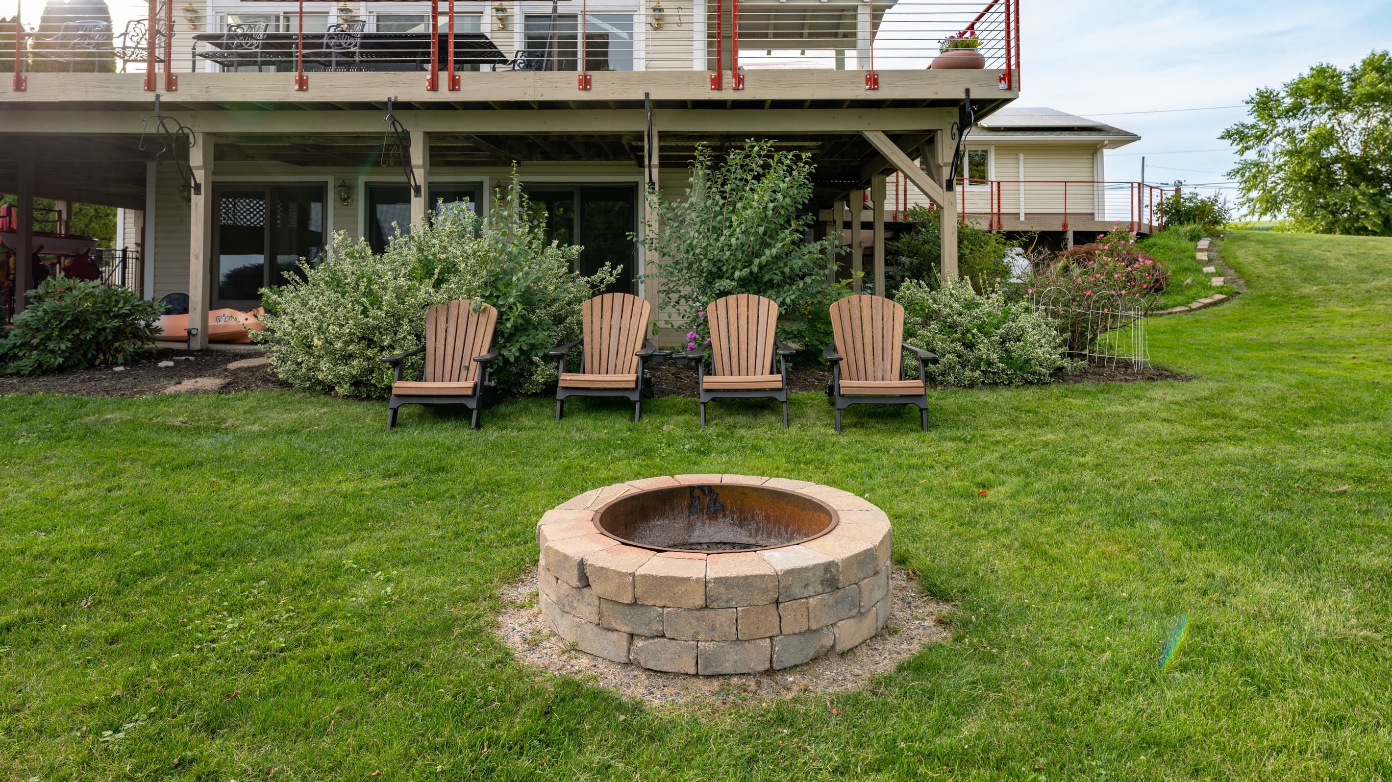 Four Adirondack chairs facing the backyard fire pit
