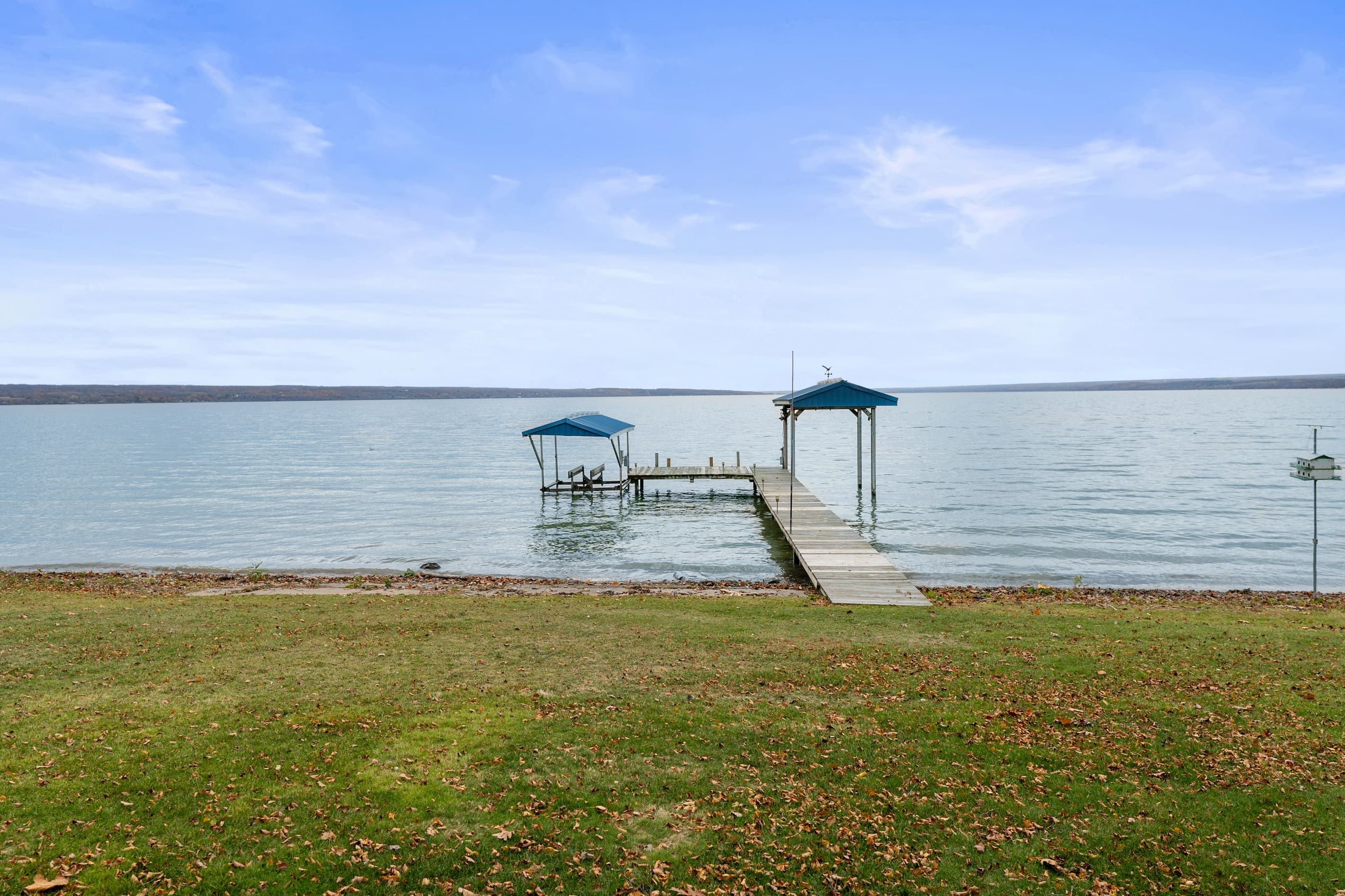Two covered boat slips beyond the grassy lawn
