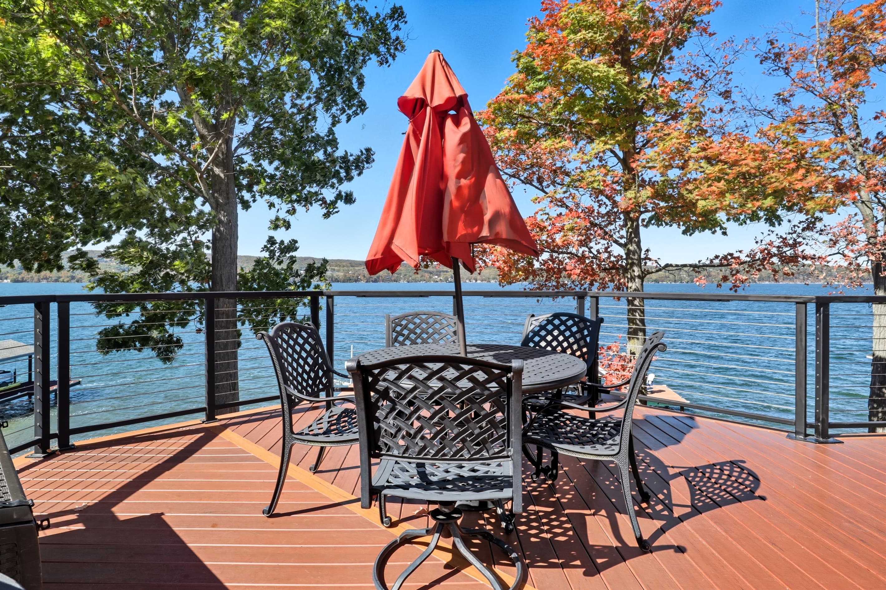 Deck dining table beneath red umbrella