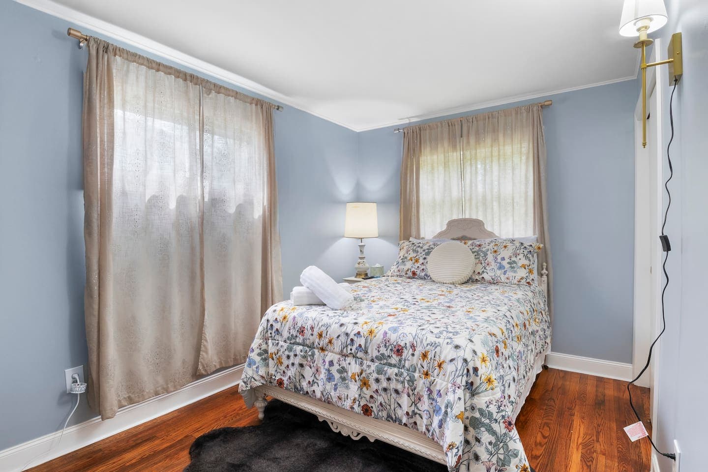 Floral bedspread beneath sheer curtains