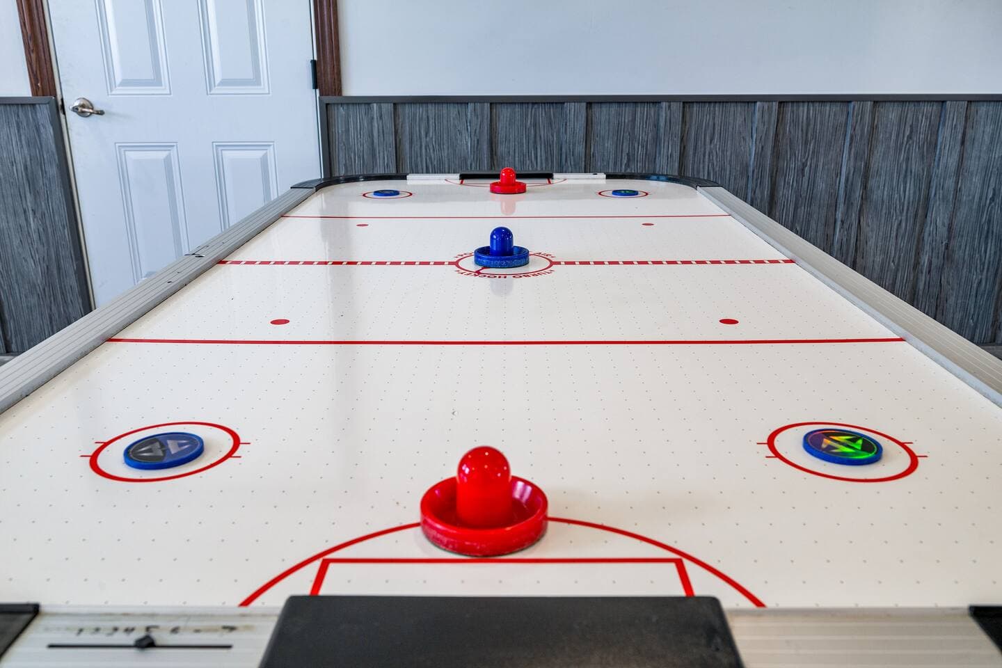 Air hockey table beside paneled wall