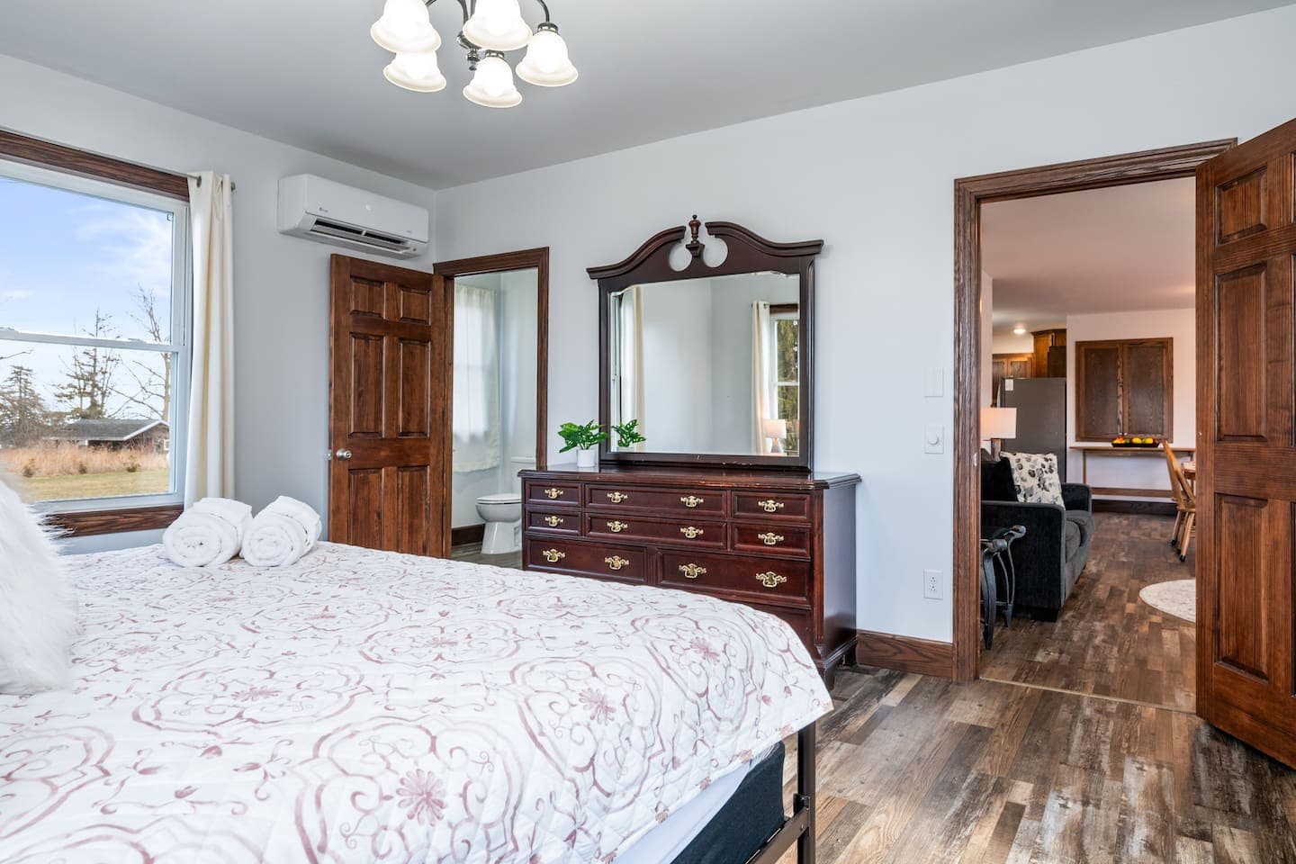 Bed facing wooden dresser and doorway