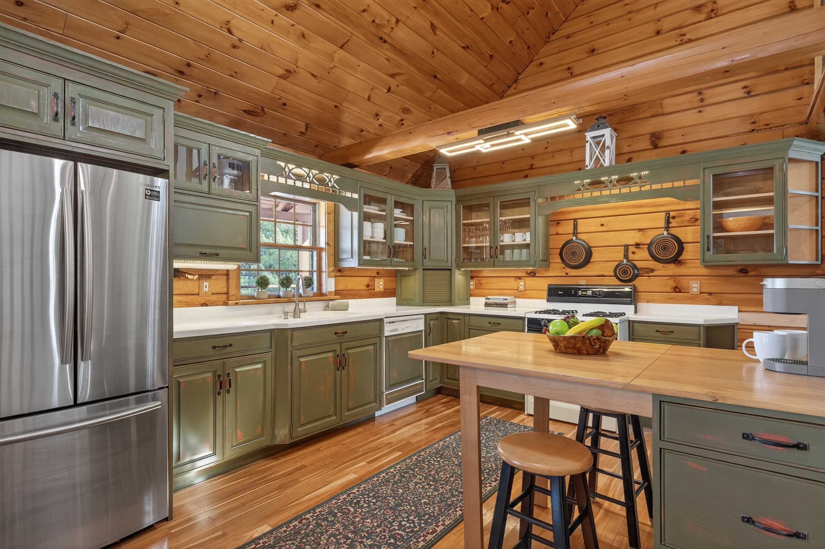 Green kitchen cabinetry with stainless steel range