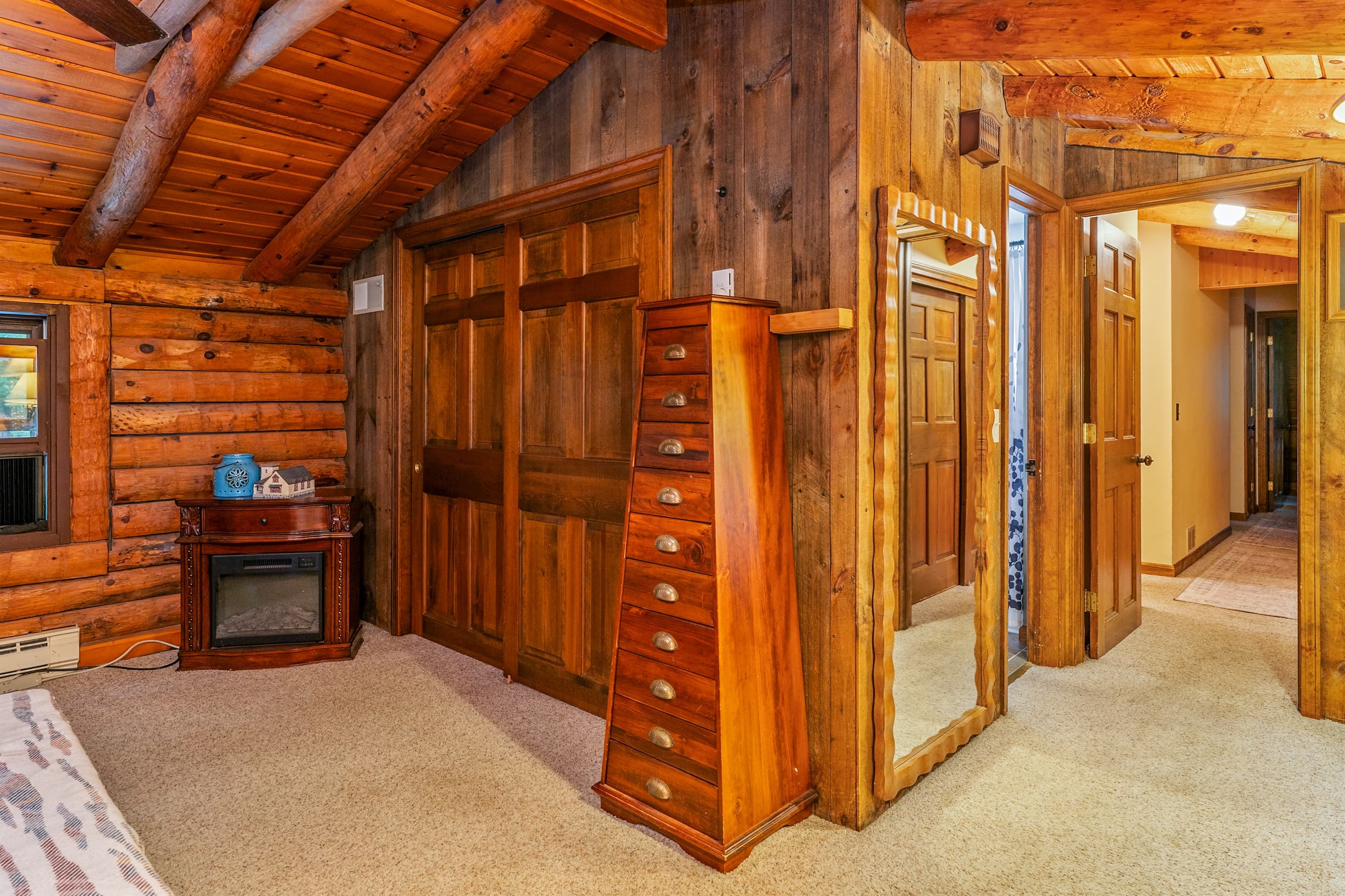 King bedroom with electric fireplace and wood walls