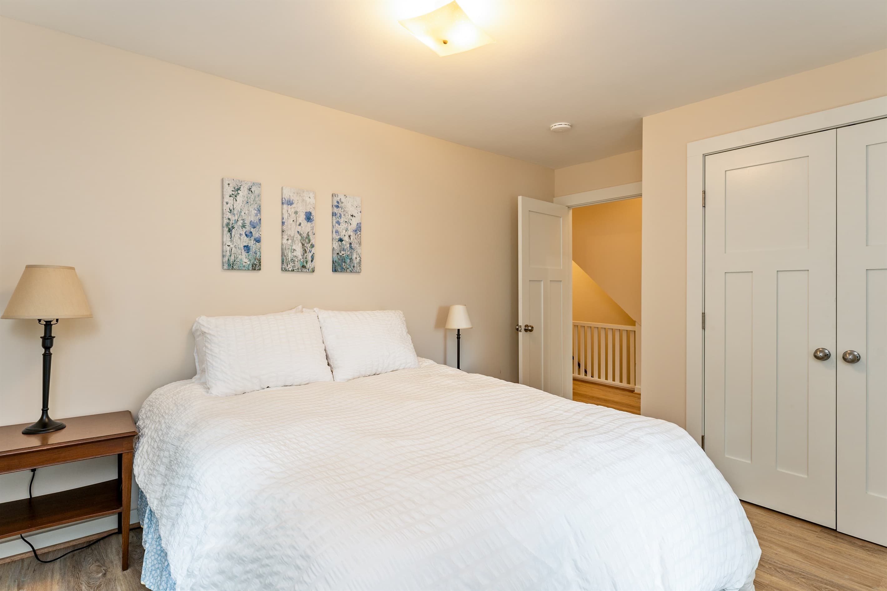 Bedroom with neutral bedding and open floor space