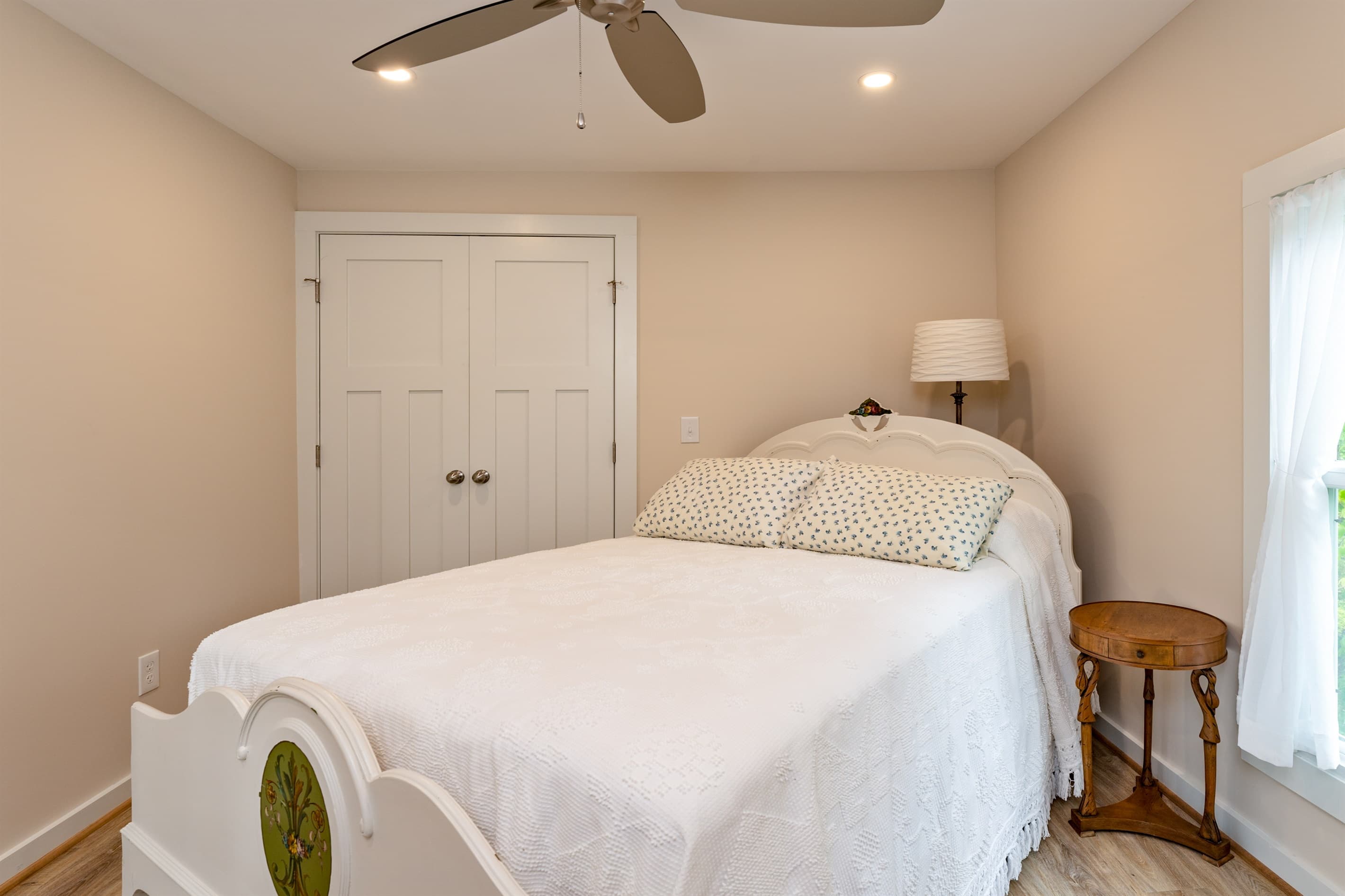 Bedroom with white wooden bed frame and ceiling fan