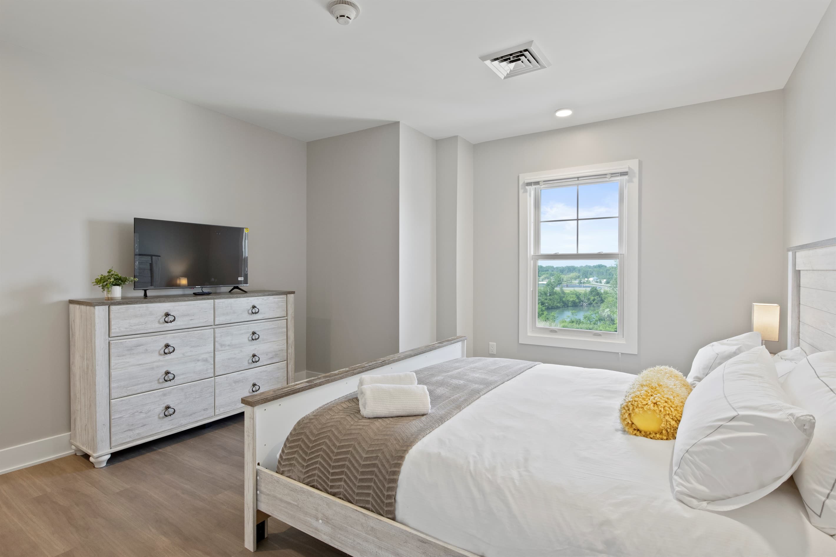Sunlit bedroom with light wood dresser