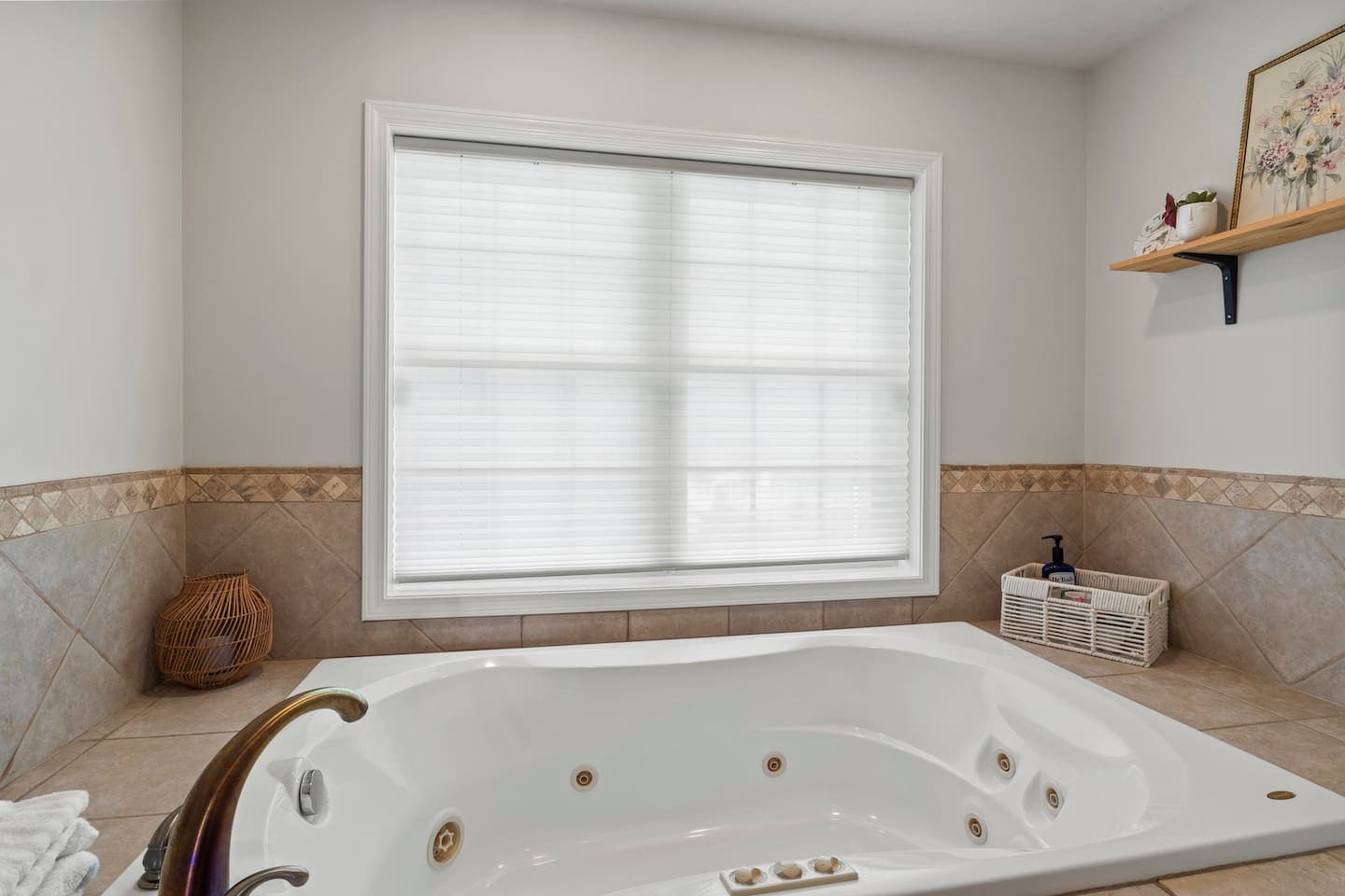 Tiled jetted bathtub beneath a large window