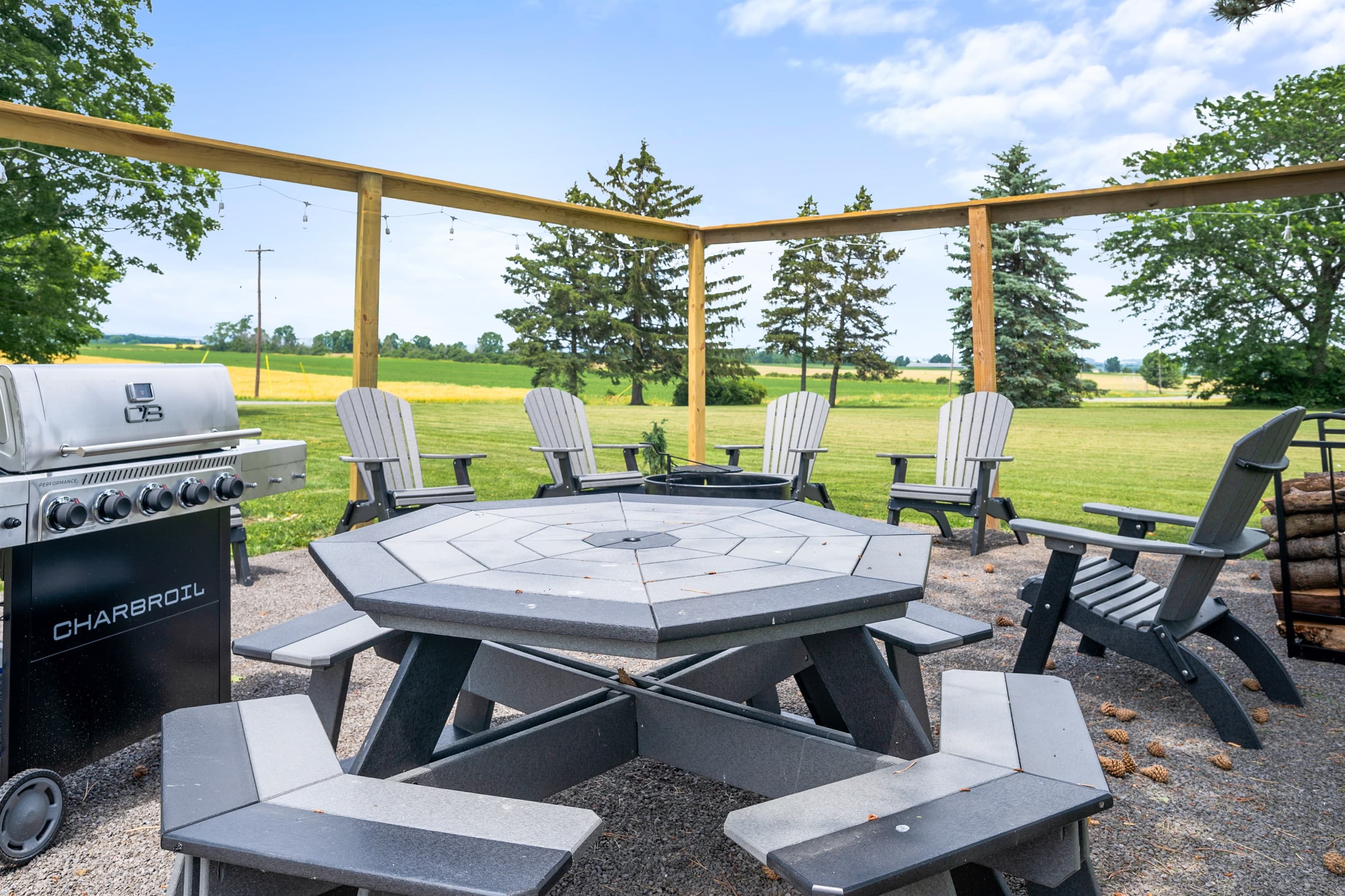 Outdoor fire pit area with a grill overlooking the lawn