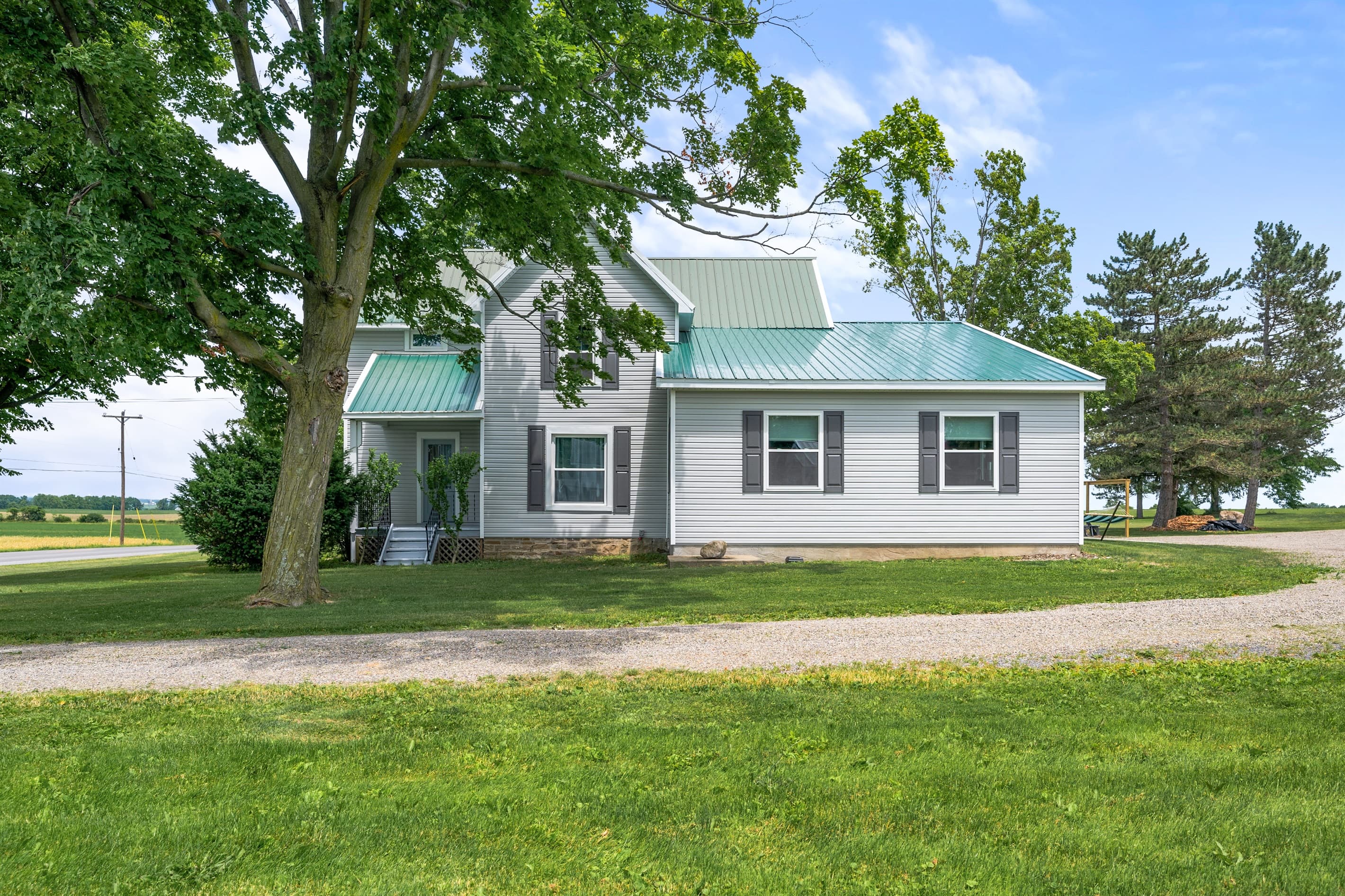 Farmhouse exterior shaded by mature trees