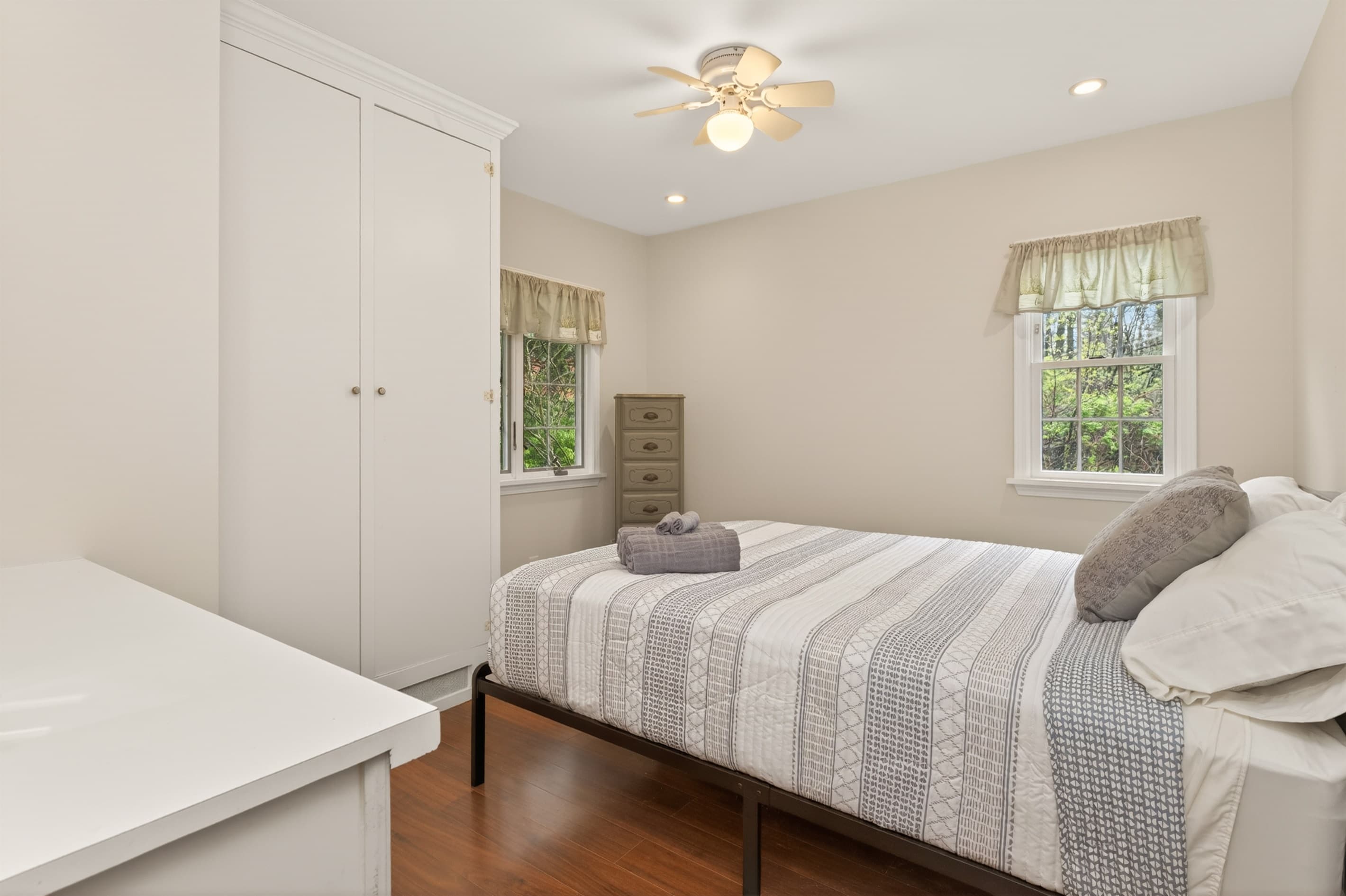 Bedroom with striped bedding and two windows