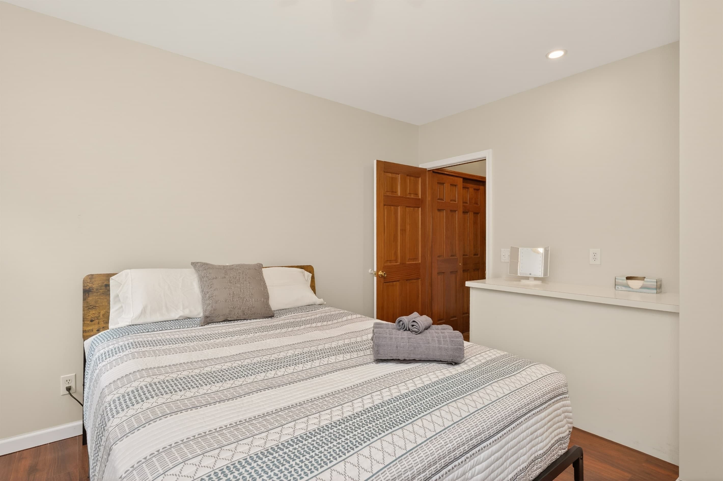 Bedroom with striped bed and wooden dresser