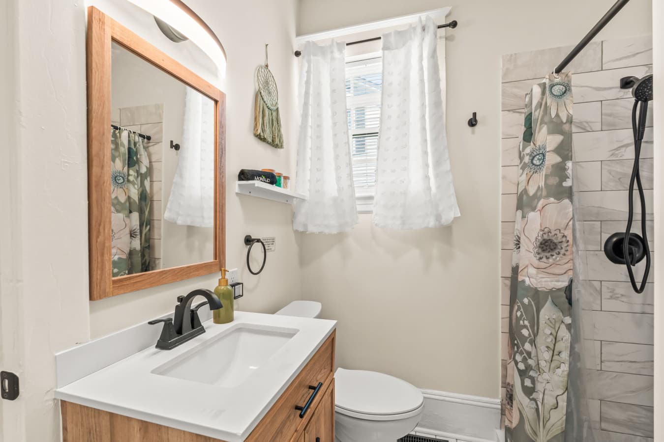 Light-filled bathroom w/ patterned shower curtain, warm finishes, & a relaxed, cheerful feel.