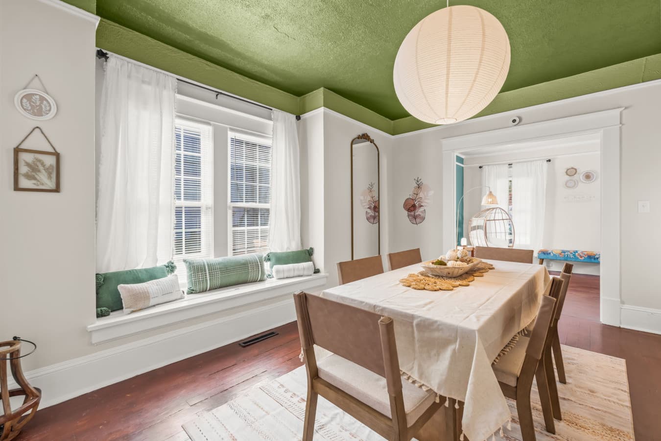Cheerful dining space w/ wood table, soft light, & windows that make meals feel relaxed and welcoming.