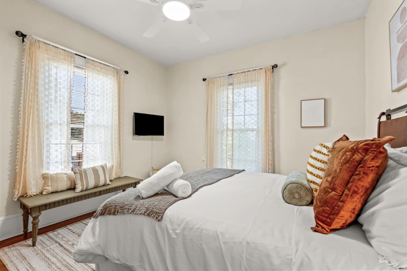 Bright bedroom w/ plush bedding, soft neutrals, & sunlight filtering in for easy mornings.