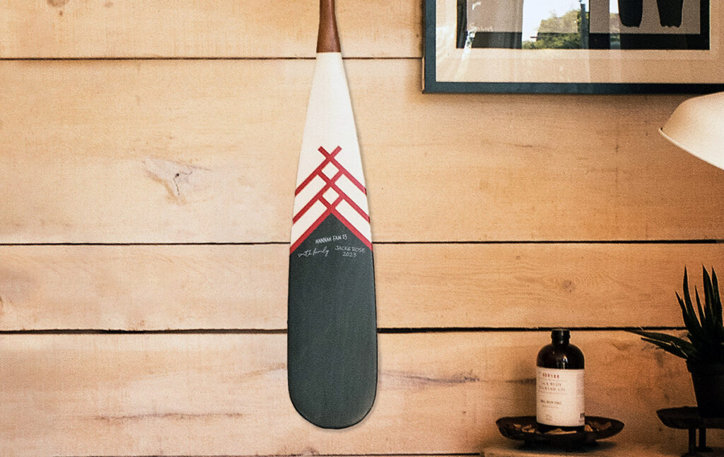 A vintage oar hangs on the wood wall of a lake cottage. 