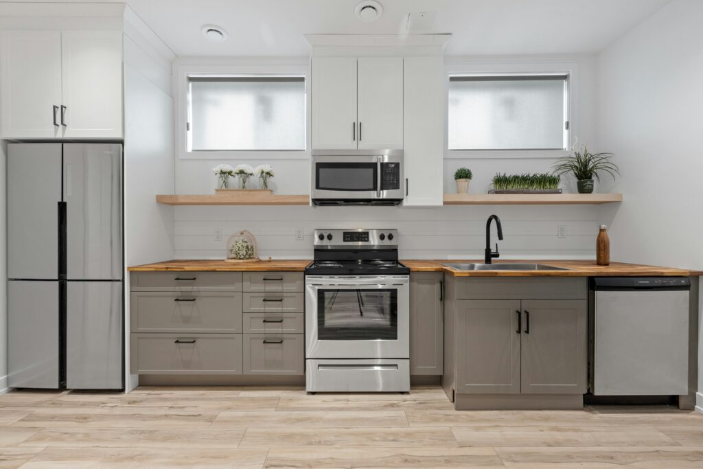 An eco friendly kitchen is stocked with energy star approved stainless steel appliances. They coordinate nicely with the painted gray cabinets and butcherblock countertops.