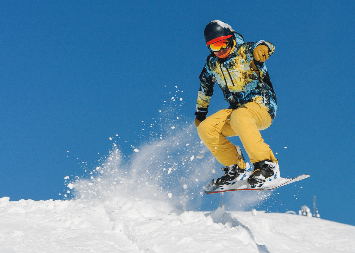 young active snowboarder in bright sportswear jumping up on a mountain slope 1 1